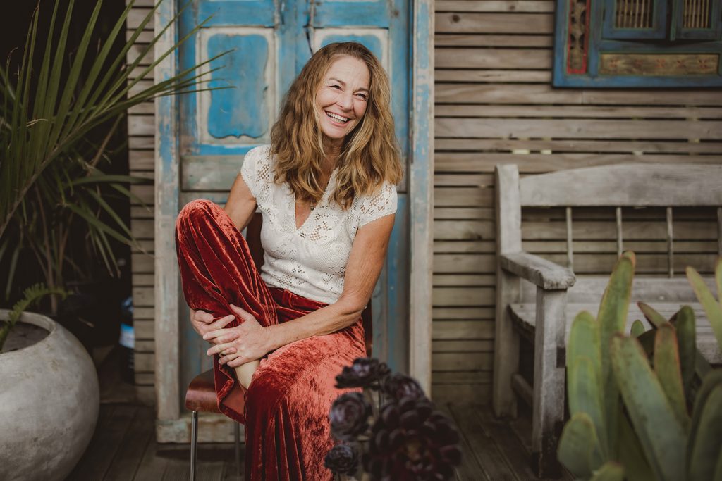 Personal branding portrait of a small business owner smiling, styled with plants and a rustic blue door backdrop