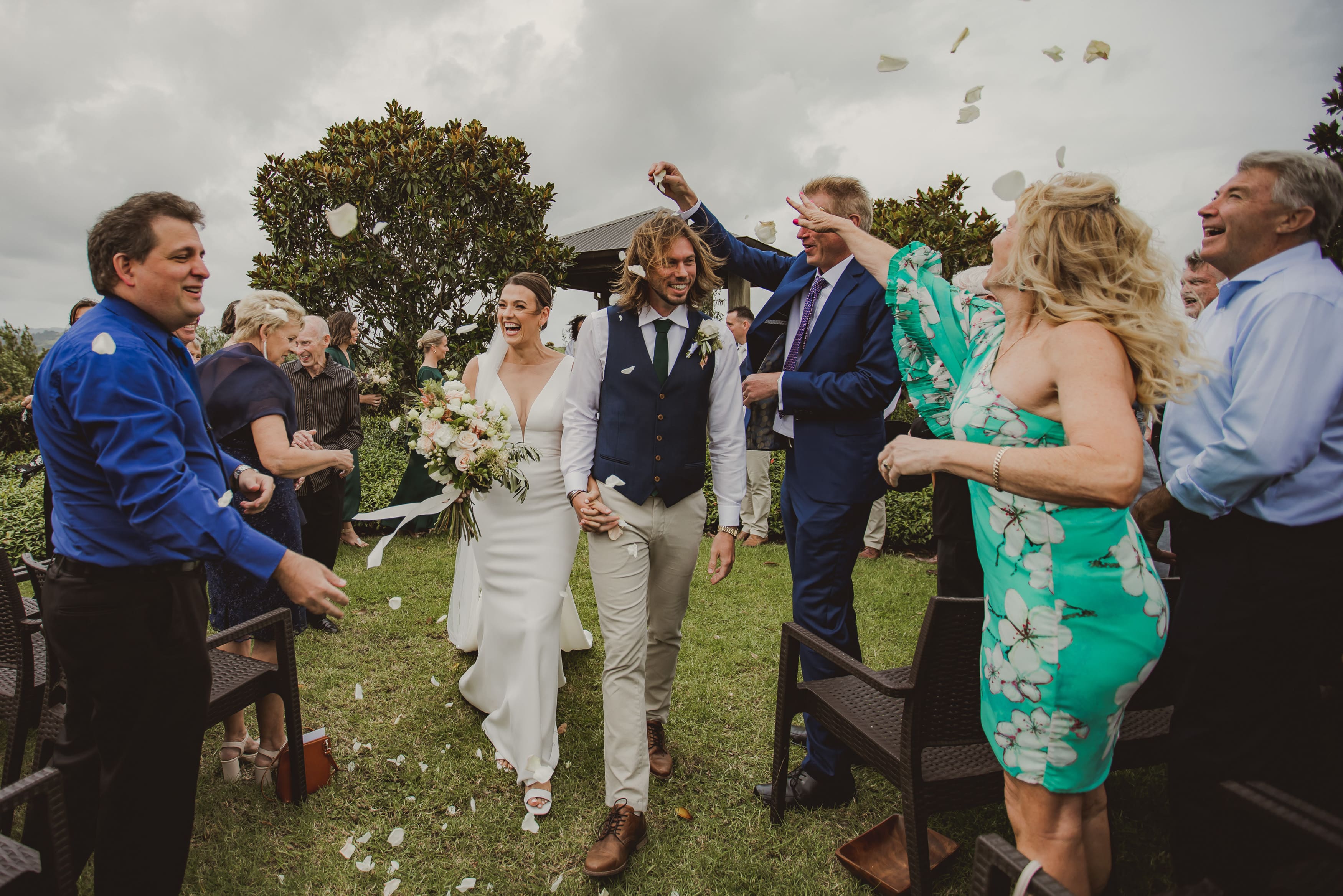 Wedding guests throwing confetti as bride and groom walk through at Plume, overcast garden party wedding exit"