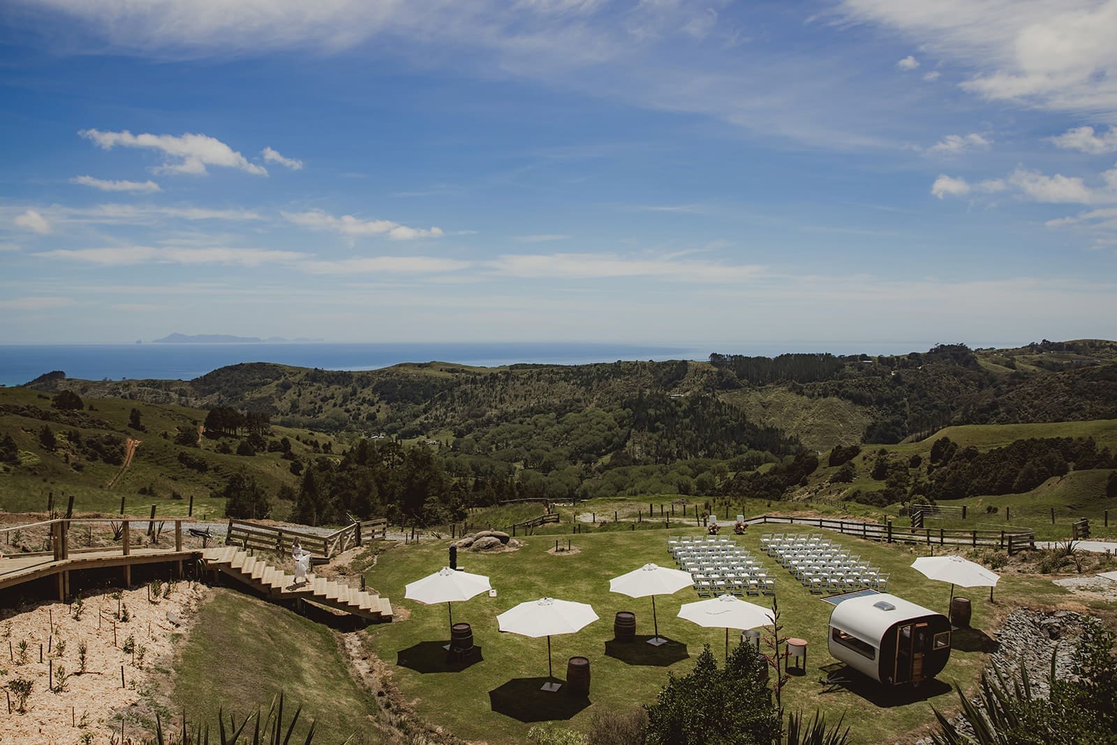Aerial view of ceremony setup at Vanderosa Farms with ocean views, white chairs and umbrellas on the hillside"
