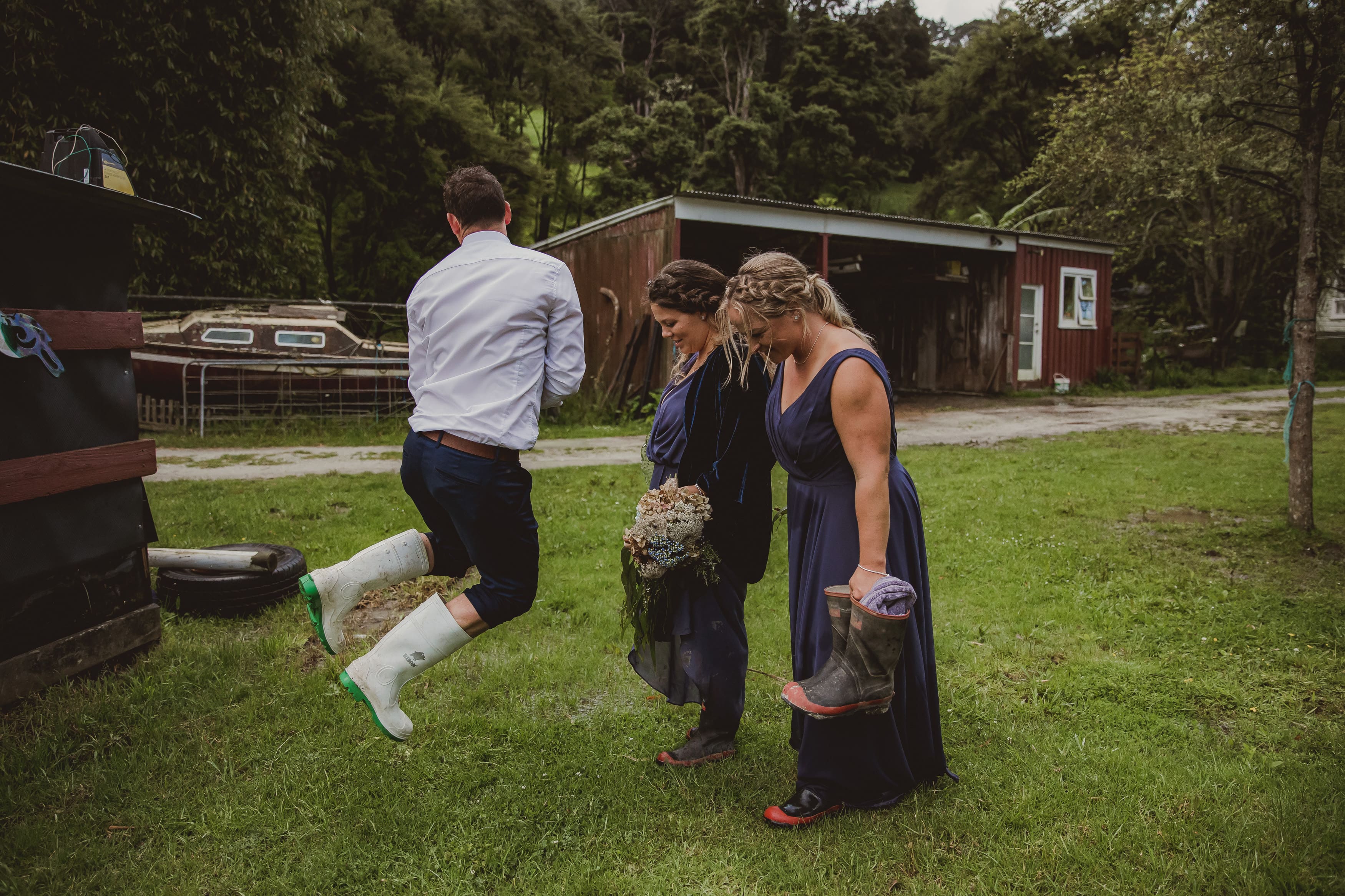 Groomsman jumping with his gumboots on at rainy wedding on the Matakana Coast 